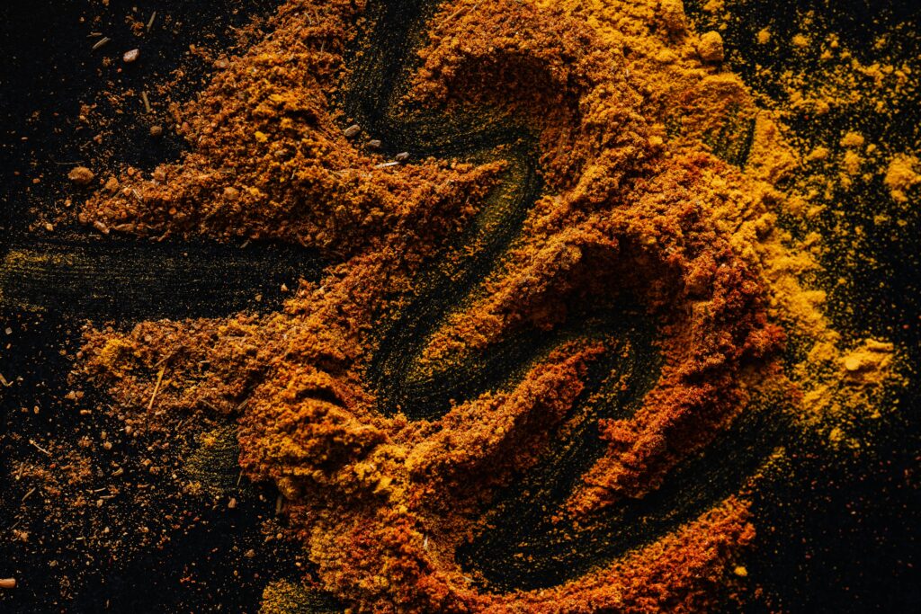 From above of creative design of smoked ground paprika and turmeric mixed together on black surface