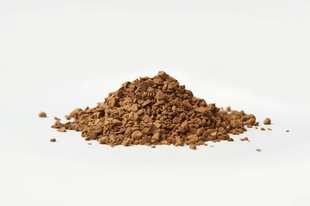 A close-up image of brown instant coffee granules on a white background.