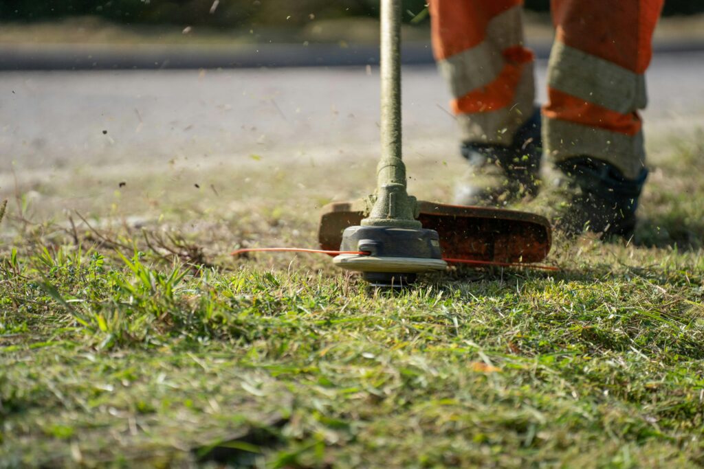 pexels-photo-11400235-11400235 Close-up of a person trimming grass with a power tool outdoors.
